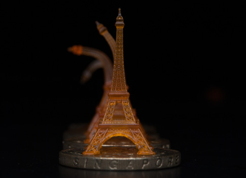 A shape-memory Eiffel tower was 3-D printed using projection microstereolithography. It is shown recovering from being bent, after toughening on a heated Singapore dollar coin. Courtesy: Qi (Kevin) Ge, MIT and Singapore University of Technology and Design