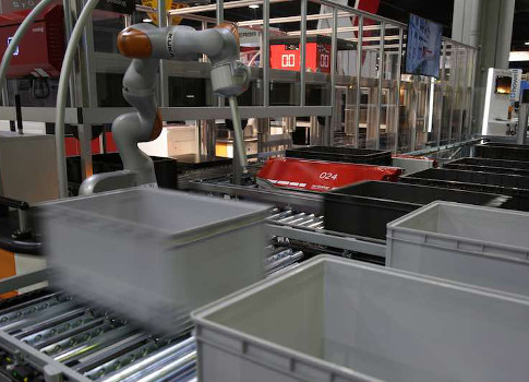 Robotic carrier systems deliver bins of goods to a collaborative robot for efficient item picking and order fulfillment. Courtesy: Robotic Industries Association (RIA), Swisslog AG