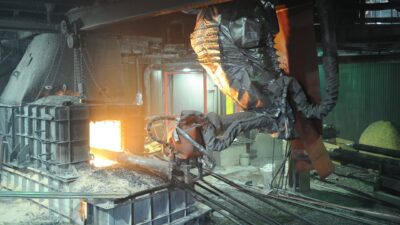 Heavy-duty robot is ceiling mounted on a 7th axis positioner and equipped with a heat-resistant suit and other specialized equipment to handle the extreme operating conditions of this furnace tapping application. Courtesy: Specialized Analysis Engineering, Inc./Robotic Industries Association