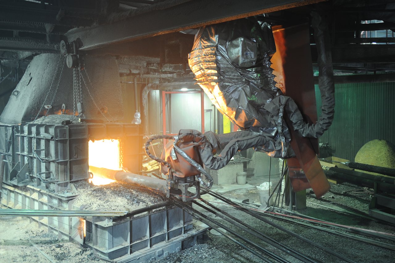 Heavy-duty robot is ceiling mounted on a 7th axis positioner and equipped with a heat-resistant suit and other specialized equipment to handle the extreme operating conditions of this furnace tapping application. Courtesy: Specialized Analysis Engineering, Inc./Robotic Industries Association