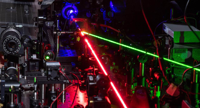 A red laser creates nonlinear effects with tiny triangles of gold. The blue beam shows the frequency-doubled light and the green beam controls the hot-electron migration. Courtesy: Rob Felt, Georgia Tech