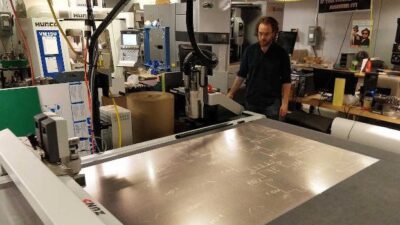 Graduate student Zach Fredin operates the Zund large-format cutter in MIT’s Center for Bit and Atoms. The machine was used to make prototypes of the face shield. Courtesy: Center for Bits and Atoms, MIT