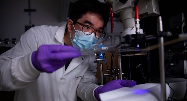 Changyeong Jeong, a graduate student in electrical engineering and computer science, measures how well light passes through a sheet of flexible transparent conductor. The material sandwiches a thin layer of silver between two “dielectric” materials, aluminum oxide and zinc oxide, producing a conductive anti-reflection coating on the sheet of plastic. Courtesy: Robert Coelius/University of Michigan Engineering