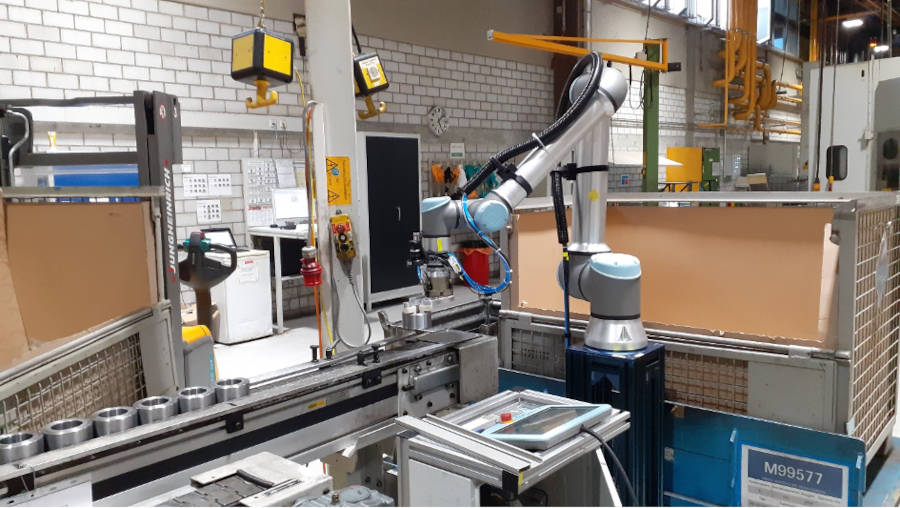Automated production process. The UR10e places a metal ring on a conveyor belt.