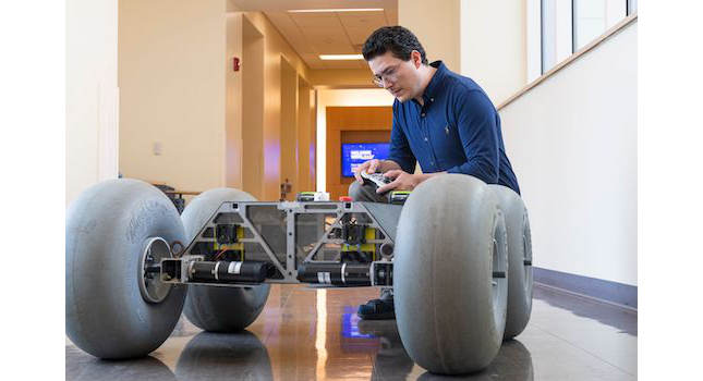 Cagri Kilic, postdoctoral research fellow in the WVU Statler College of Engineering and Mineral Resources, shows off a rover that he developed to research slips in planetary rovers. Two other researchers are applying this same technology to improve safety in retail and wholesale settings. Courtesy: WVU